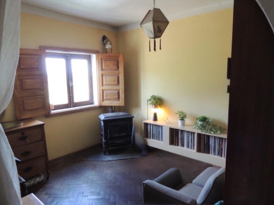A bedroom with parquet floor, wooden shutters and its own small wood burner