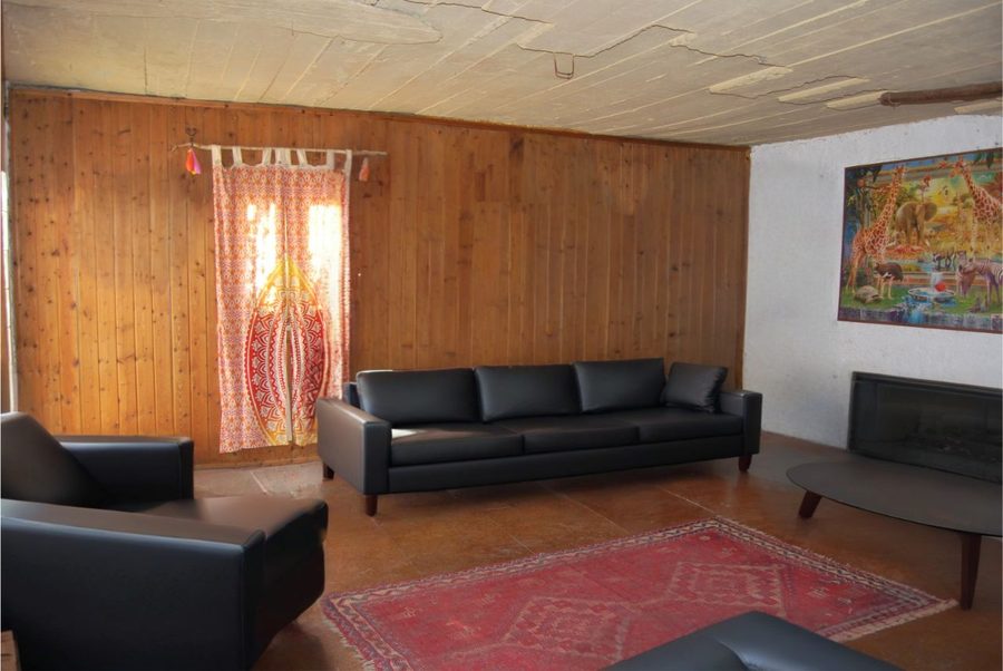 The living room — pine panelling, tiled floor, and the wood burner that heats the house